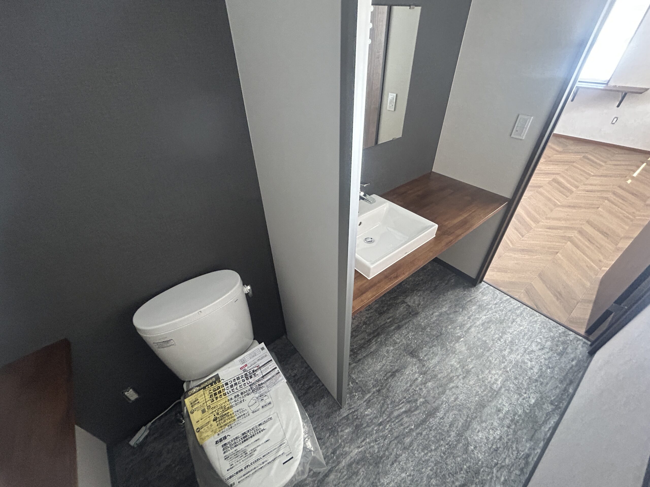 藤枝市 仕上がりの記録：トイレと洗面カウンター。濃い色の壁と木目を組み合わせた内装。