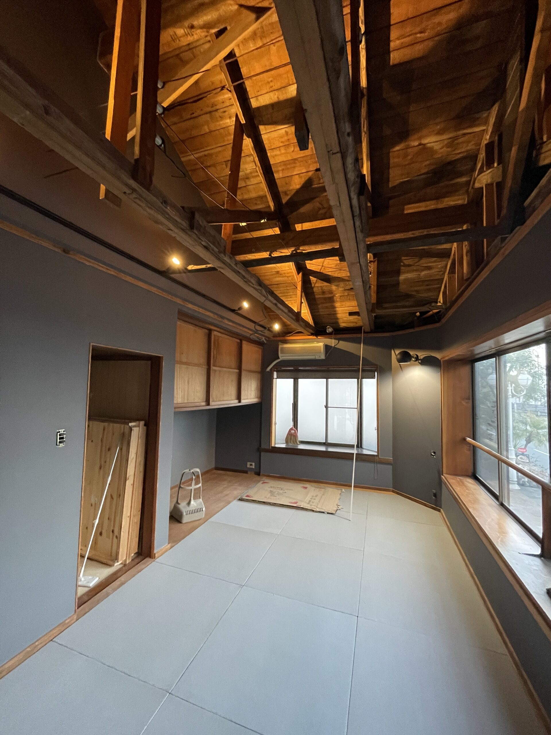 熱海市 施工中｜壁面施工後：梁を見せた空間と、壁面・床の作業状況。